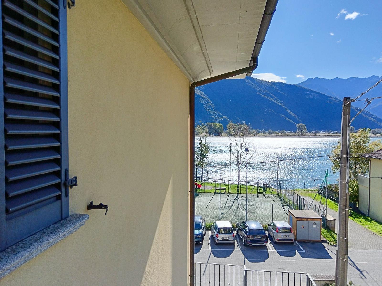 Blick von Balkon auf See und Berge mit Parkplatz und Spielplatz.