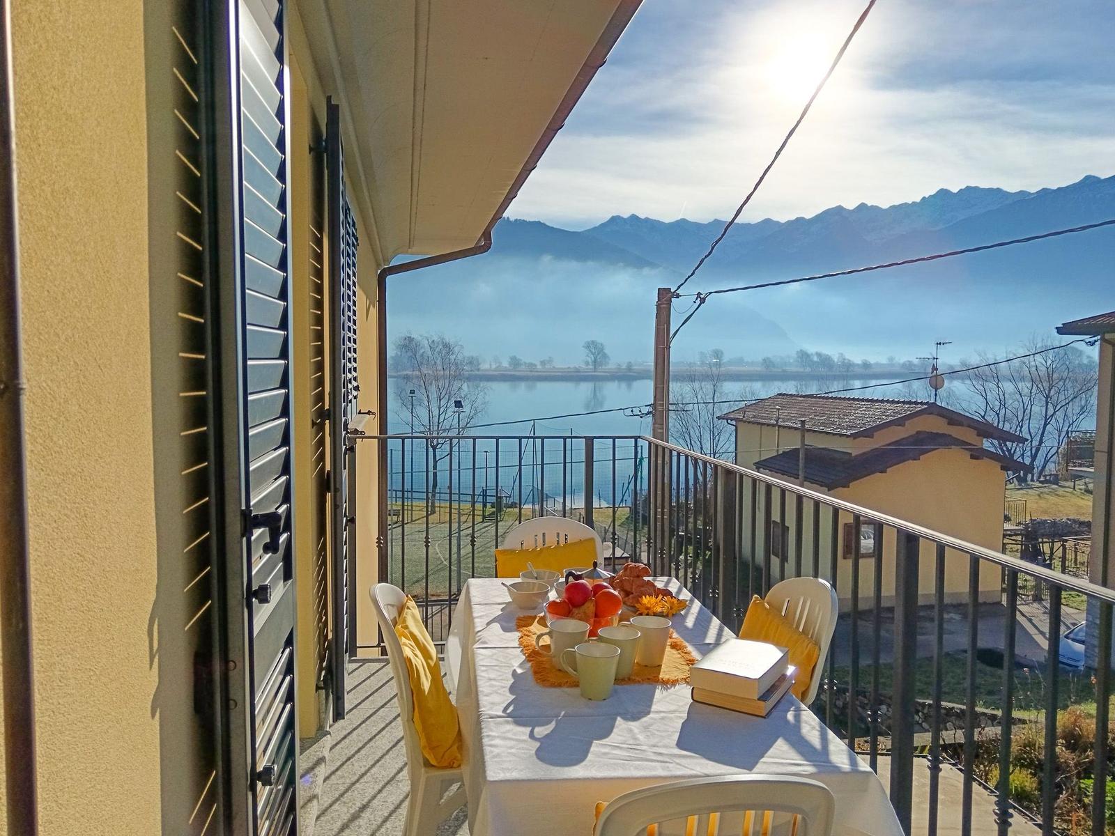 Terrasse mit Tisch und Stühlen, Blick auf See und Berge.