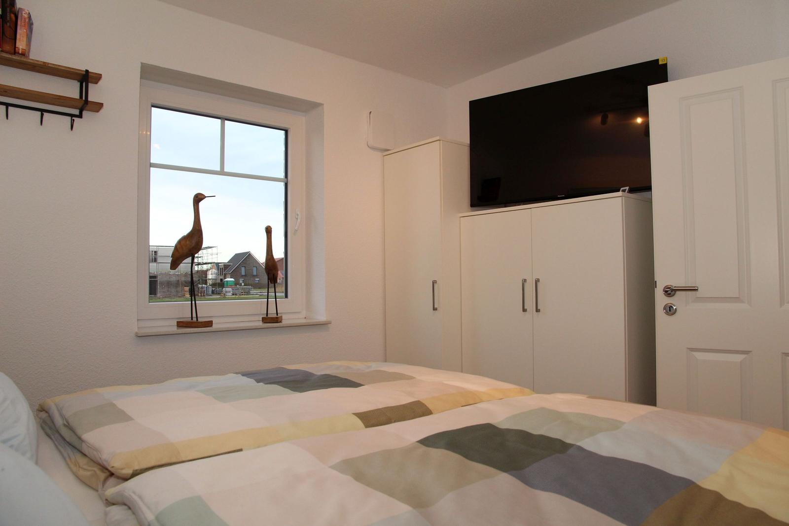 Schlafzimmer mit Bett, Fenster, Kleiderschrank und Fernseher.