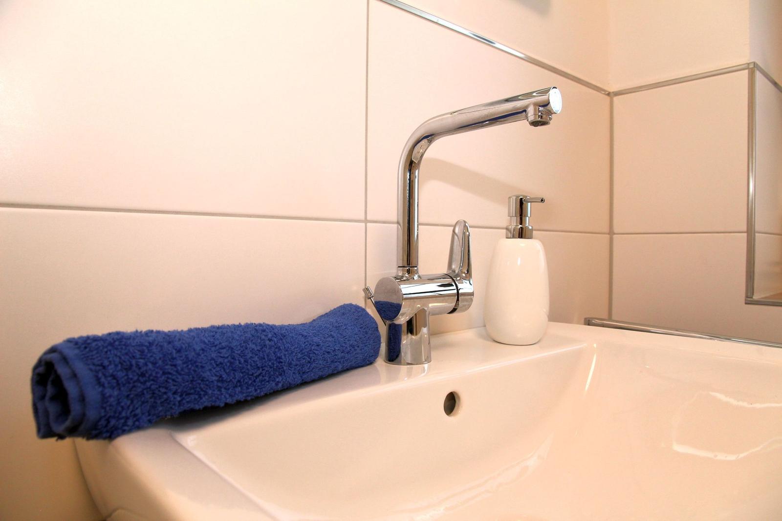 Waschbecken mit blauem Handtuch und chromfarbenem Wasserhahn