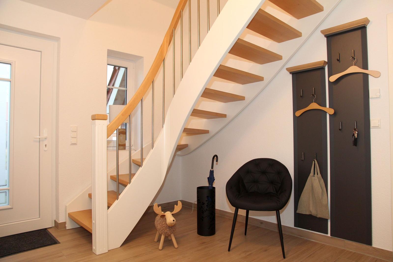 Haus mit Treppe, Stuhl, Regal und Eingangsbereich.