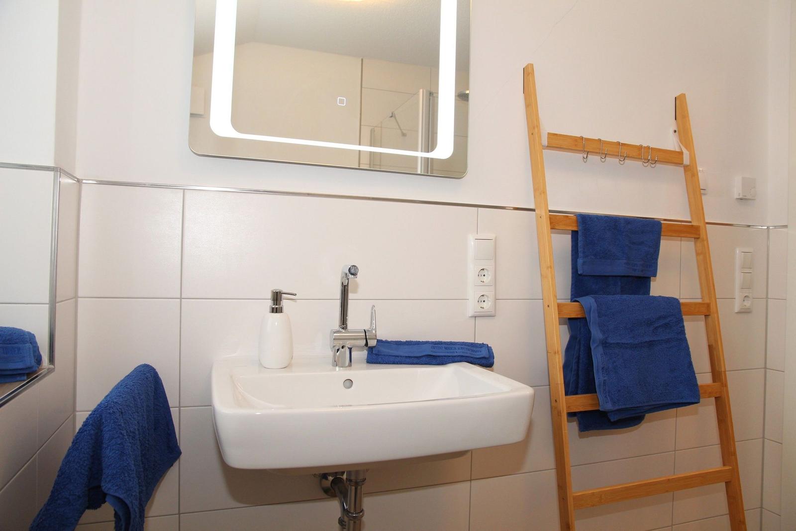 Badezimmer mit Waschbecken, Spiegel und Handtuchständer.