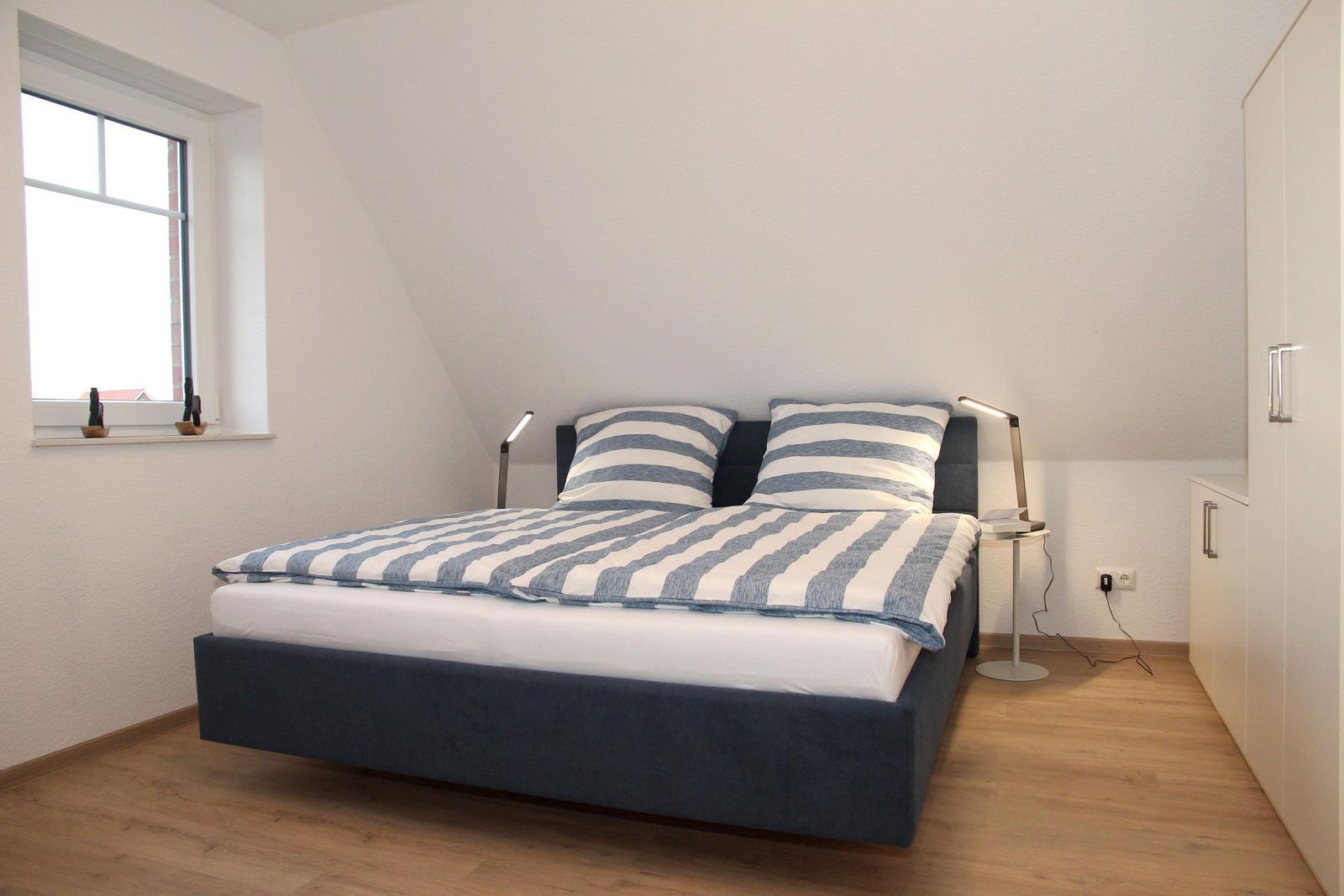 Schlafzimmer mit Doppelbett, Fenster und Schrank.