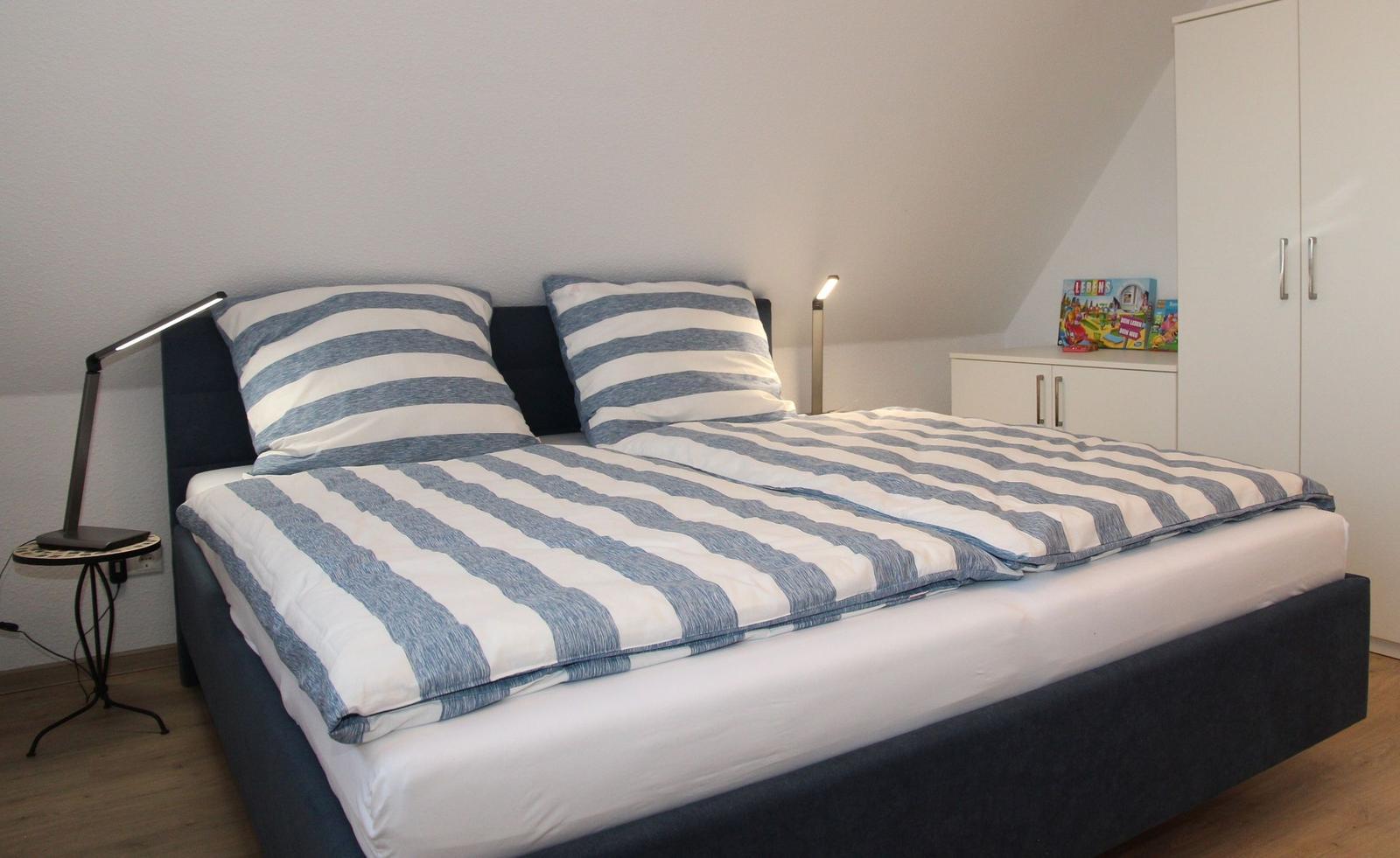 Schlafzimmer mit Doppelbett, Nachttisch und Kleiderschrank.