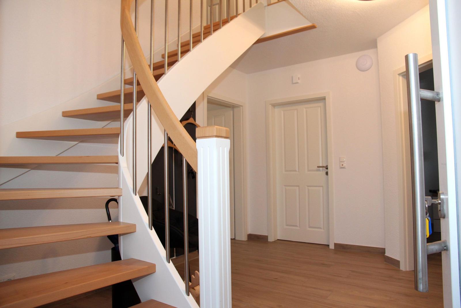 Haus mit Holztreppe und weißer Wand. Tür und Boden sind sichtbar.