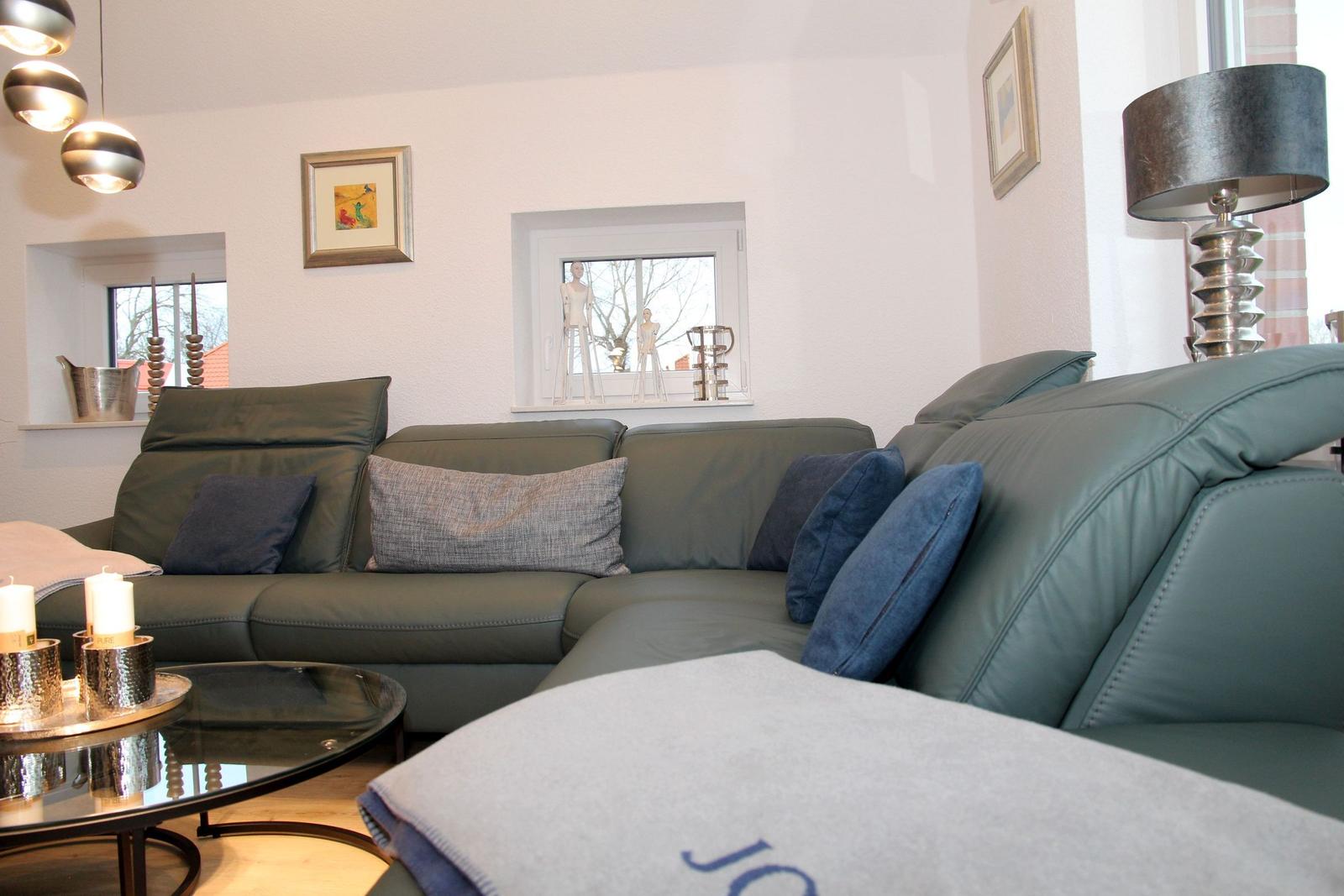 Ein Wohnzimmer mit einem grauen Sofa, einem runden Tisch und einer Lampe.
