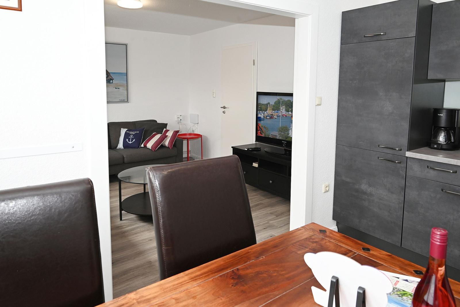 Wohnung mit Essbereich, Wohnzimmer, Fernseher und Küchenzeile.