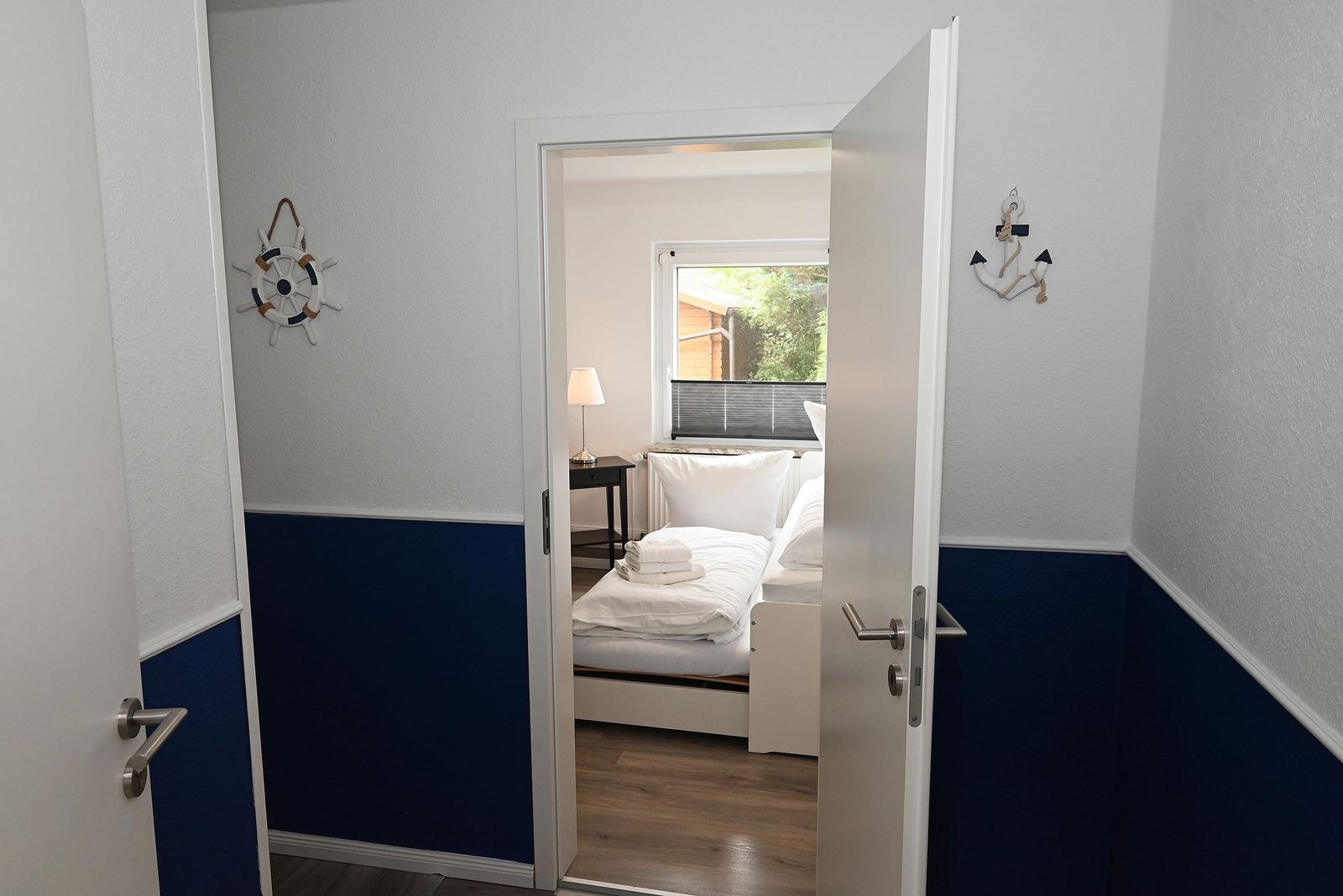 Schlafzimmer mit Blick auf Garten, blaue Wandgestaltung und Schiffsruder-Dekoration.