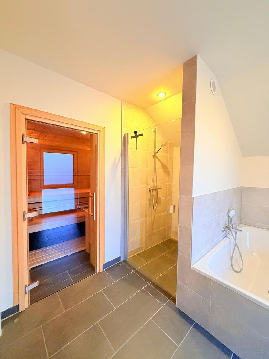 Dusche, Badewanne und Sauna in einem Raum mit Holz- und Fliesenverkleidung.
