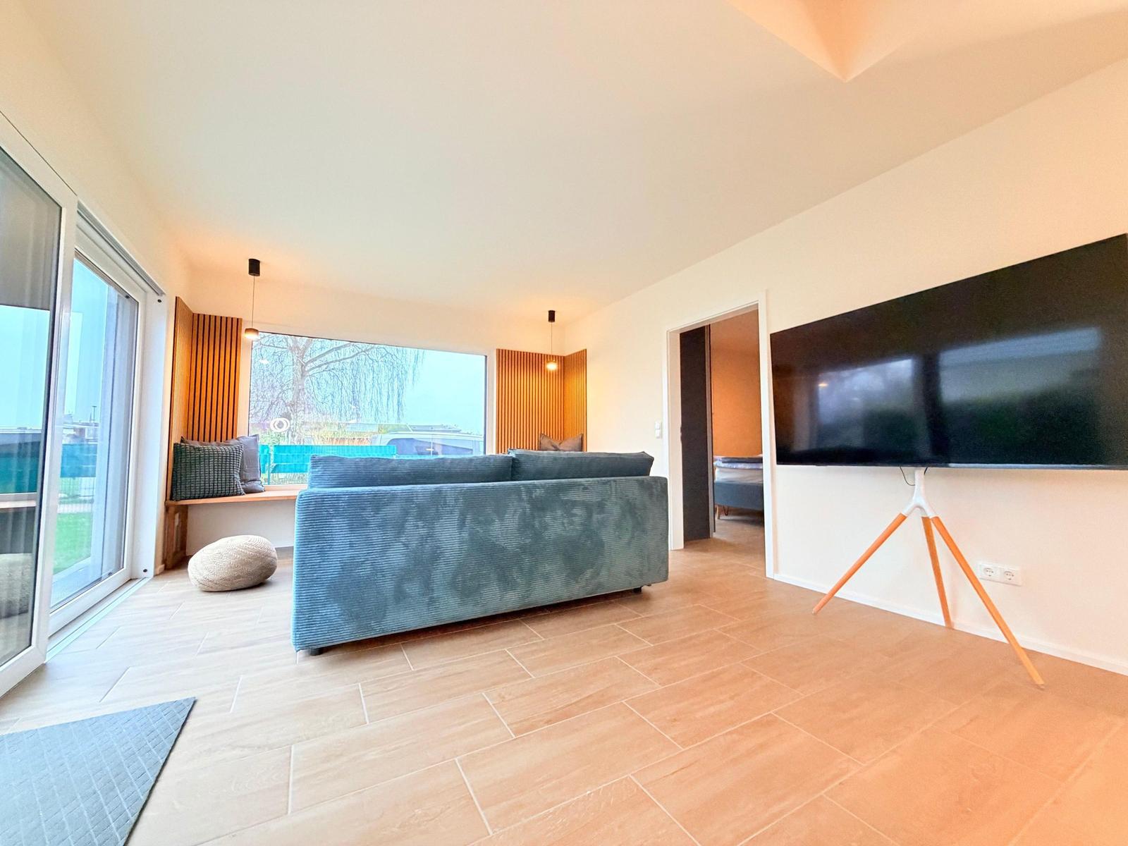 Wohnzimmer mit Sofa, TV und Blick auf Garten.