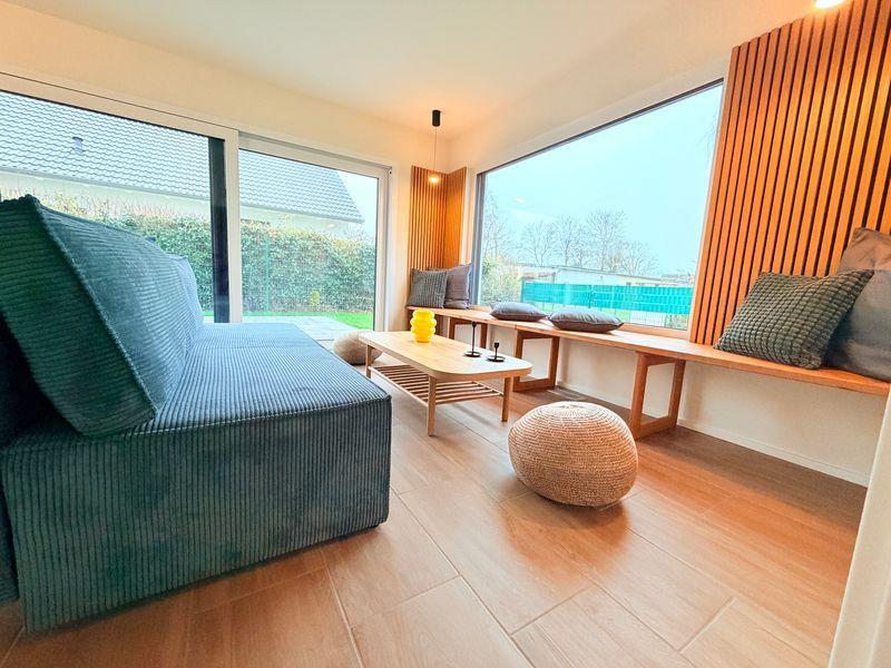 Wohnzimmer mit Sofa, Sitzbank und großem Fensterblick auf Garten