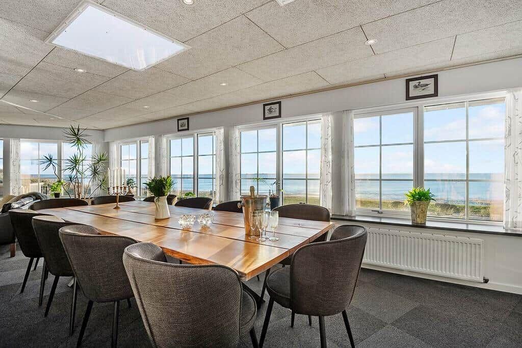 Dining room with long table and chairs, large windows with sea view