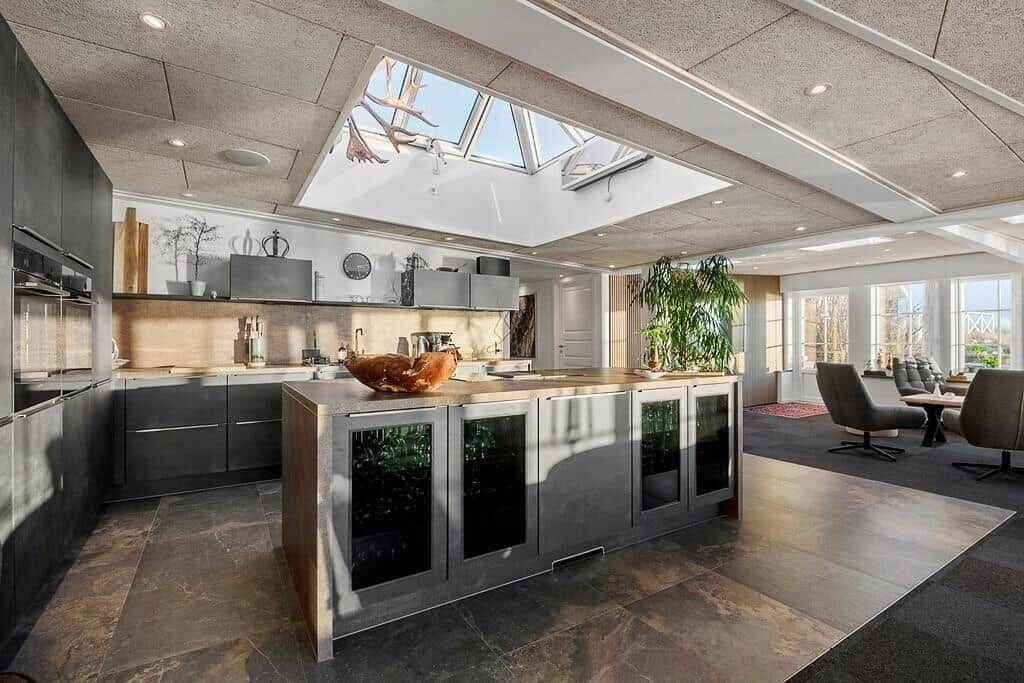 Kitchen with island, skylight, and seating area in background.