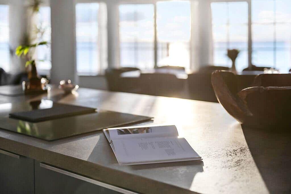 Kitchen island with open book and view of the sea.