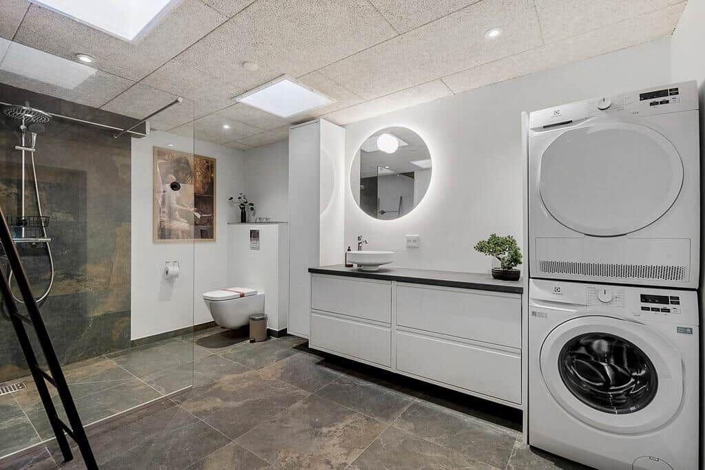 Bathroom with shower, toilet, sink, and washer-dryer unit.