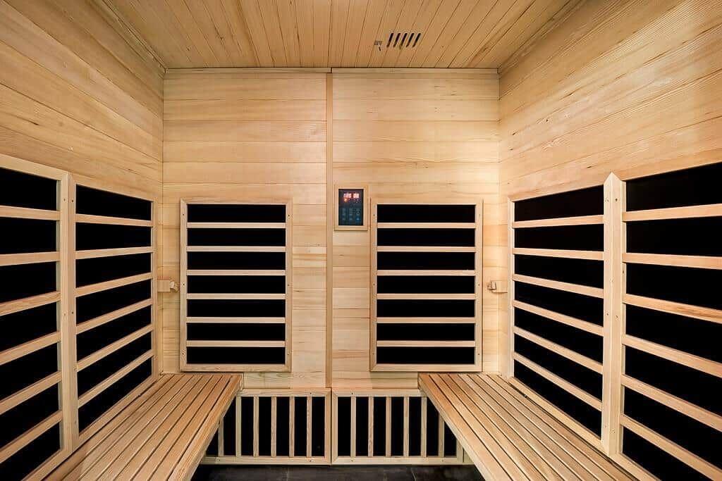 Interior of a sauna with wooden benches and heating elements on the walls.