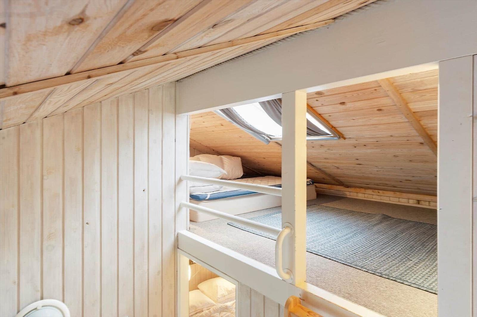 Upper bunk with mattress and window in attic. Lower bunk with mattress.