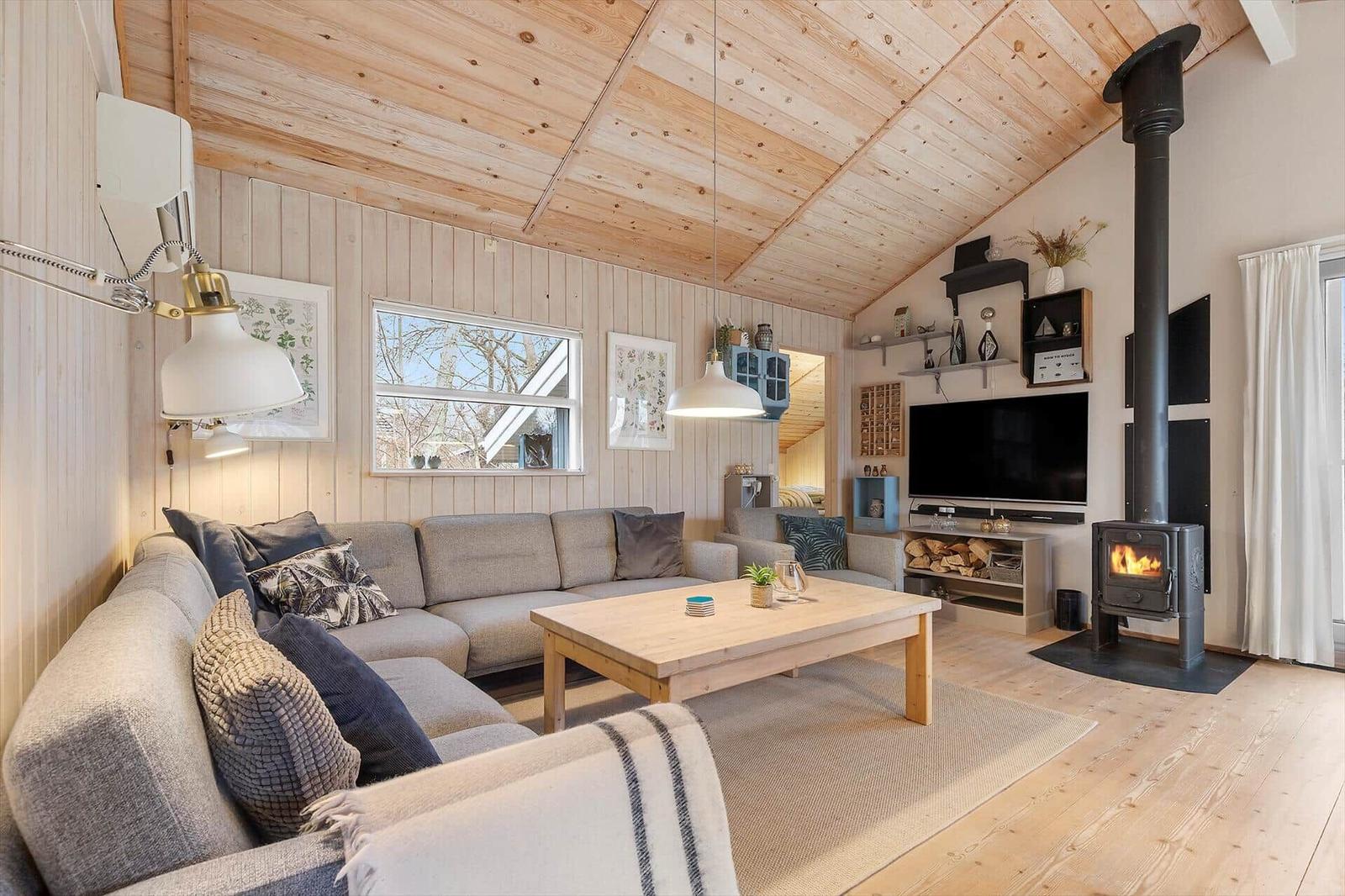 Living room with sofa, fireplace, and TV. Wooden ceiling and floor.