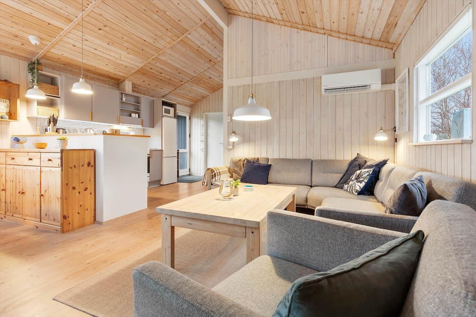 Living and kitchen area with wooden ceiling, sofa, and dining table.