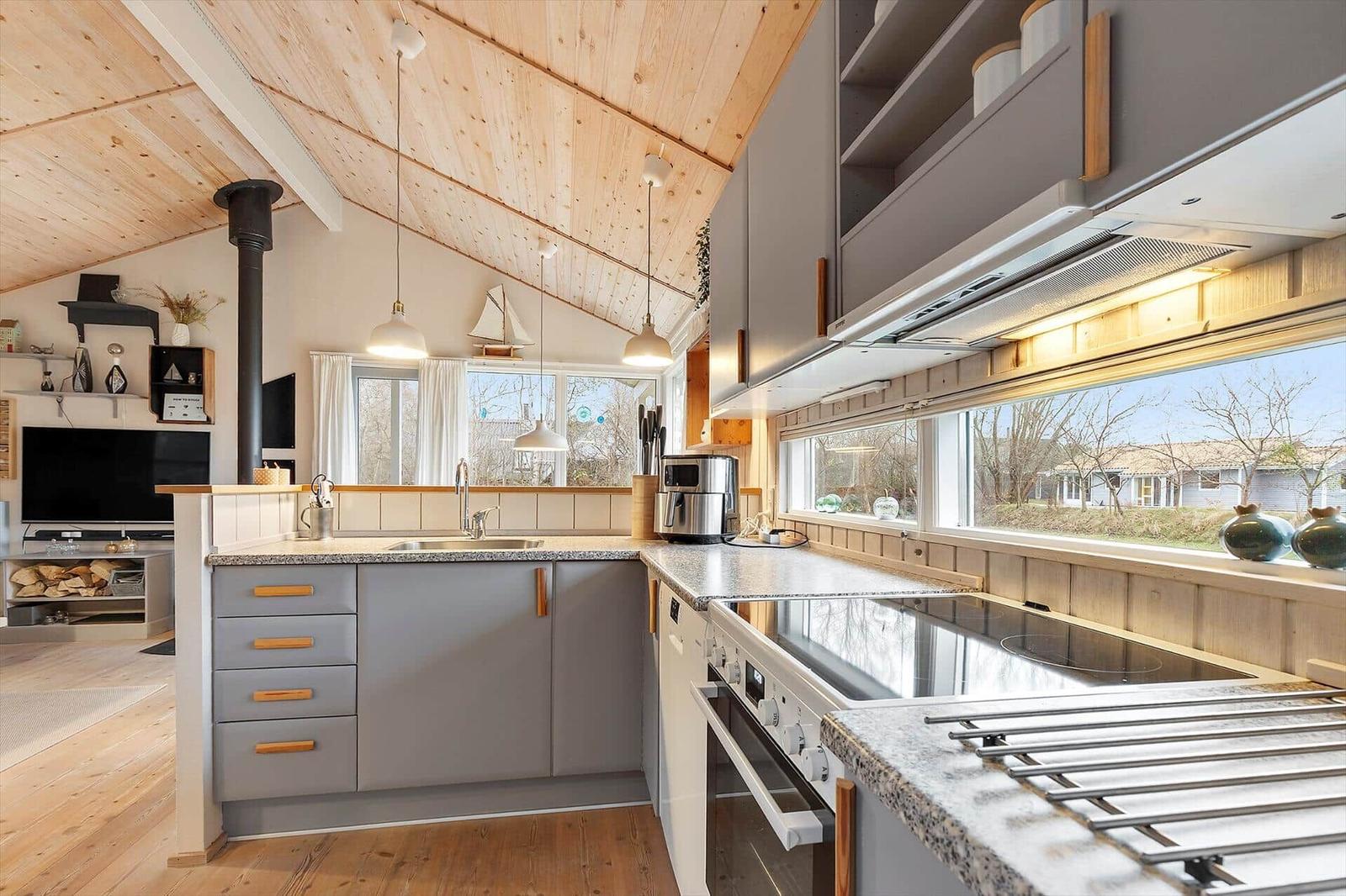 Kitchen with gray cabinets, stainless steel appliances, and wooden ceiling. Large windows with outdoor view.