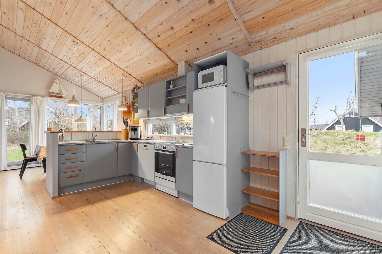 Kitchen with wooden floor, gray cabinets, and kitchen island. Passage to terrace with view of outdoor area.