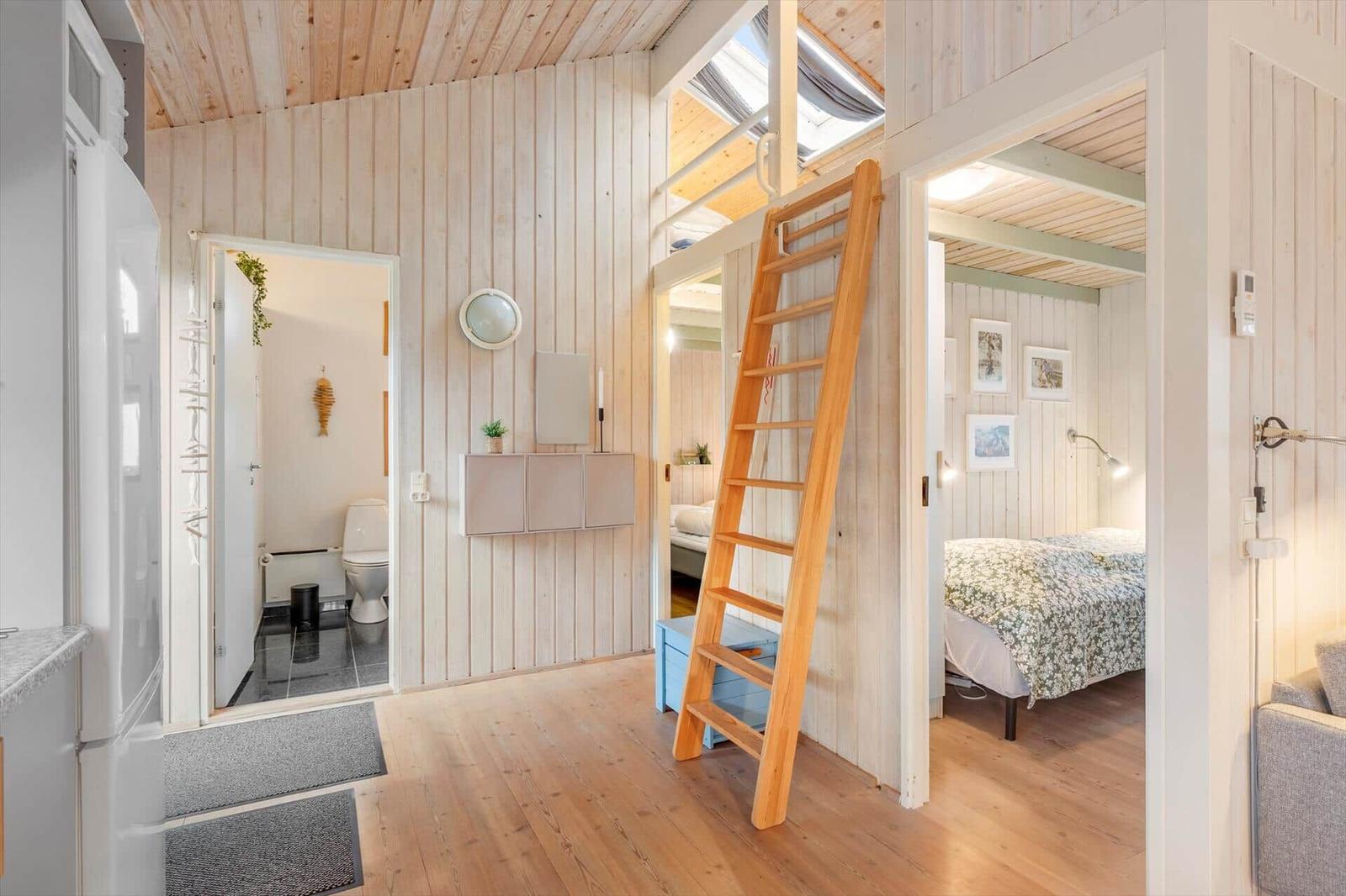 Living area with upper sleeping space, bathroom, and kitchenette. Wooden walls and floor.