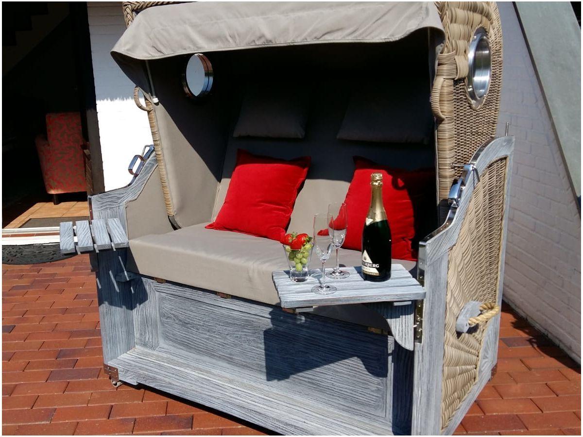 Ein gerahmter Liegestuhl mit roten Kissen und einer Flasche Champagner auf der Ablage.