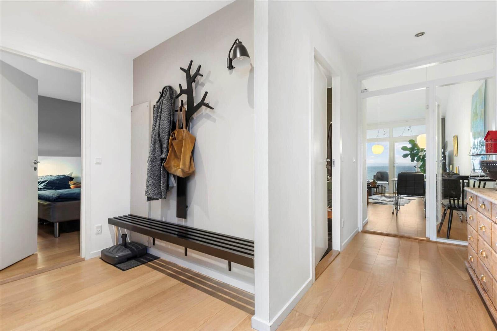Entryway with bench, coat rack, and view into bedroom and dining area.