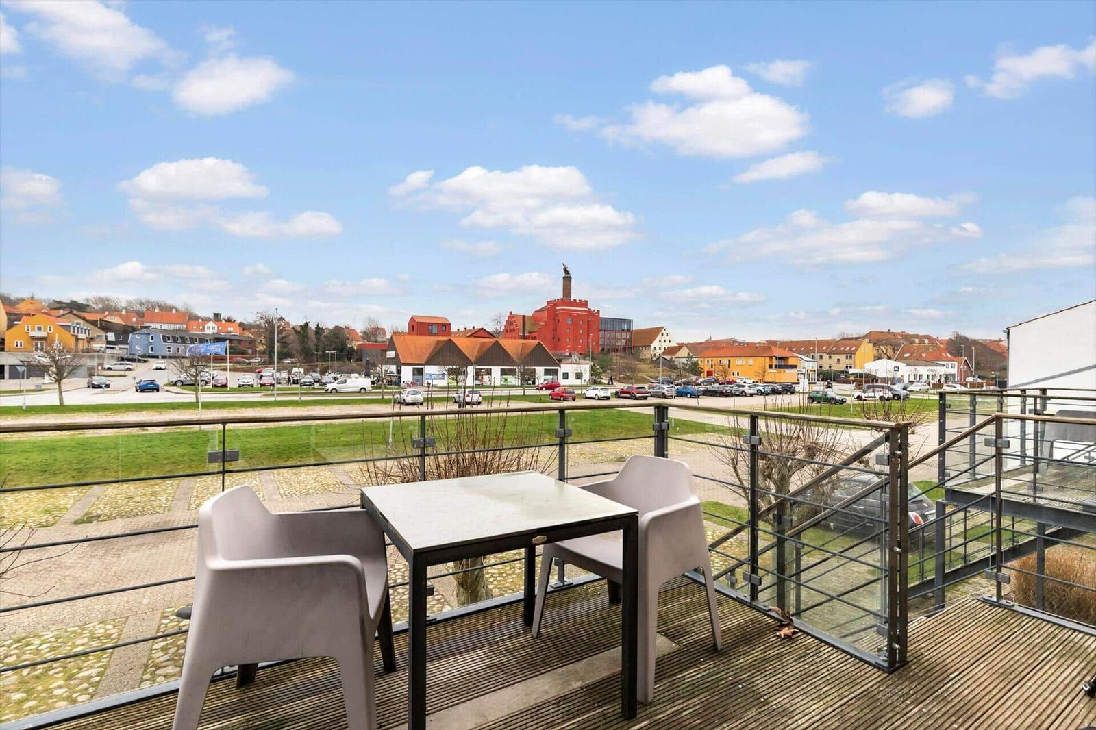 Terrace with table and chairs offers view of town and green areas.