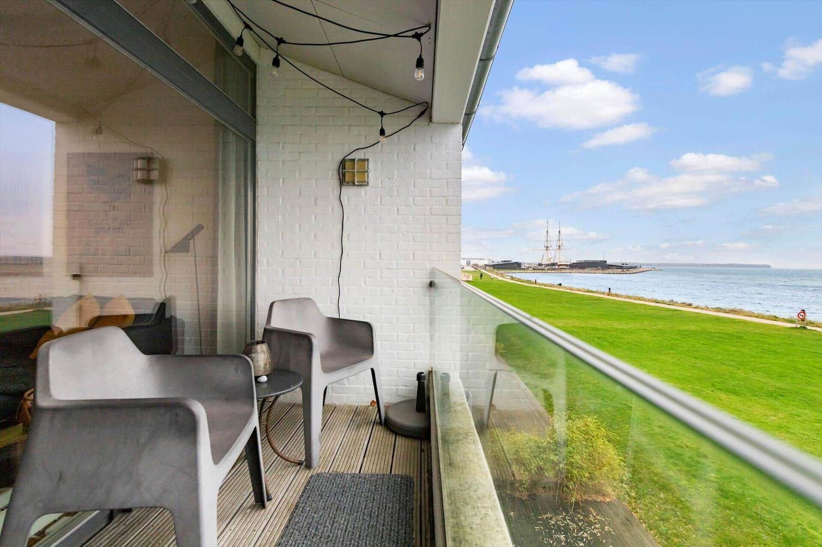 Terrace with seating and view of grassy area and harbor.