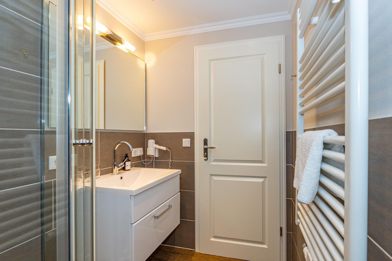 Badezimmer mit Dusche, Waschbecken und Handtuchheizung.