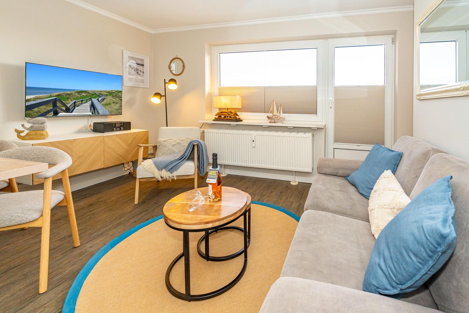 Wohnzimmer mit Sofa, Couchtisch und Fernseher an der Wand.