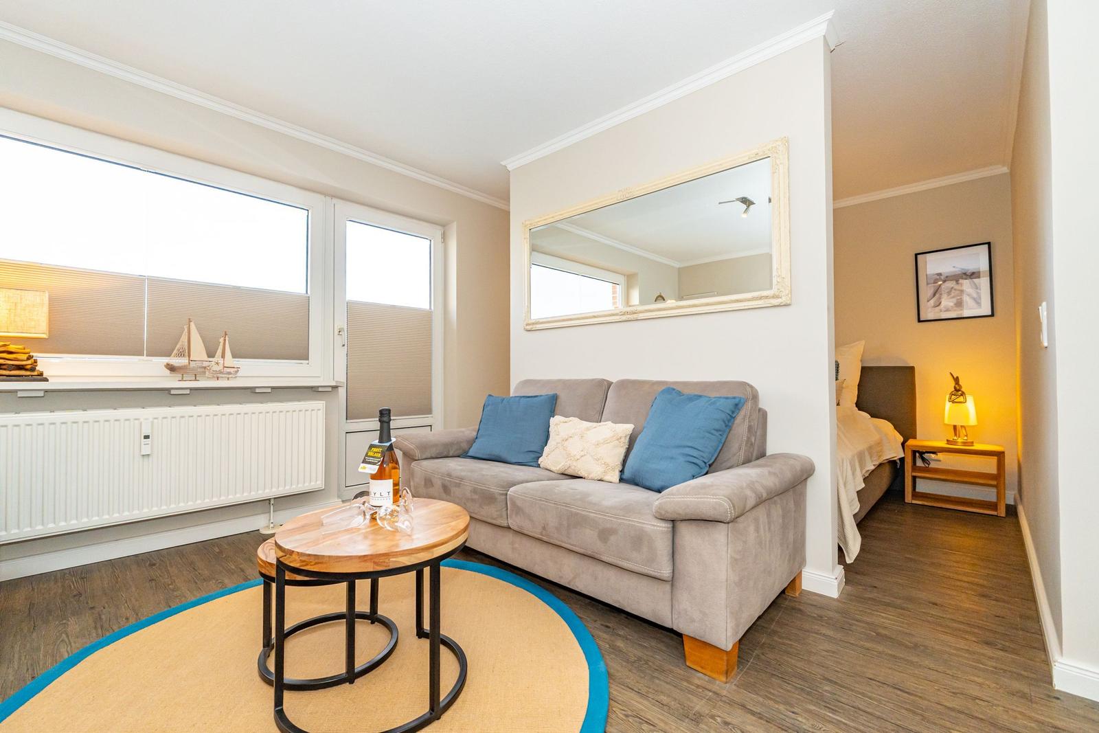 Wohnbereich mit Sofa, Tisch und Blick auf Schlafzimmer