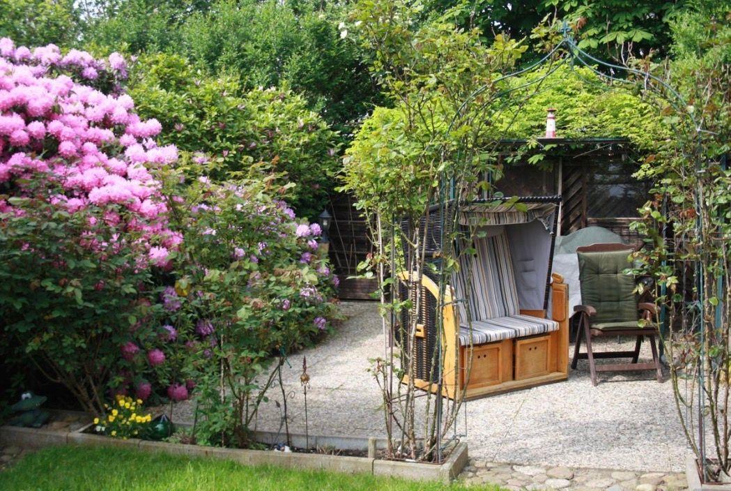 Garten mit Blumen, Pavillon und Sitzgelegenheiten.