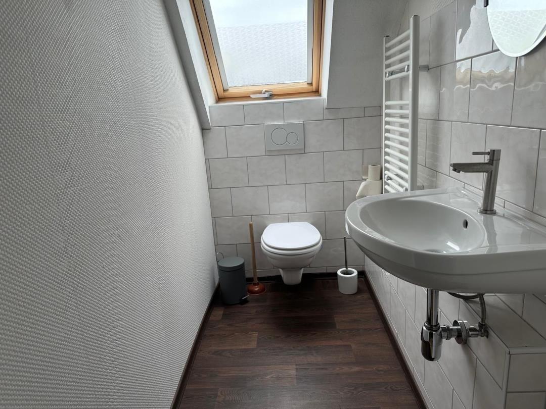 Badezimmer mit Toilette, Waschbecken und Dusche unter Dachfenster