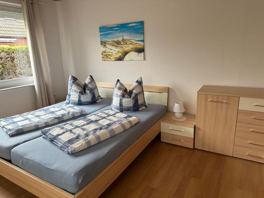 Zimmer mit Doppelbett, Nachttisch und Schrank. Fensterblick auf Garten.