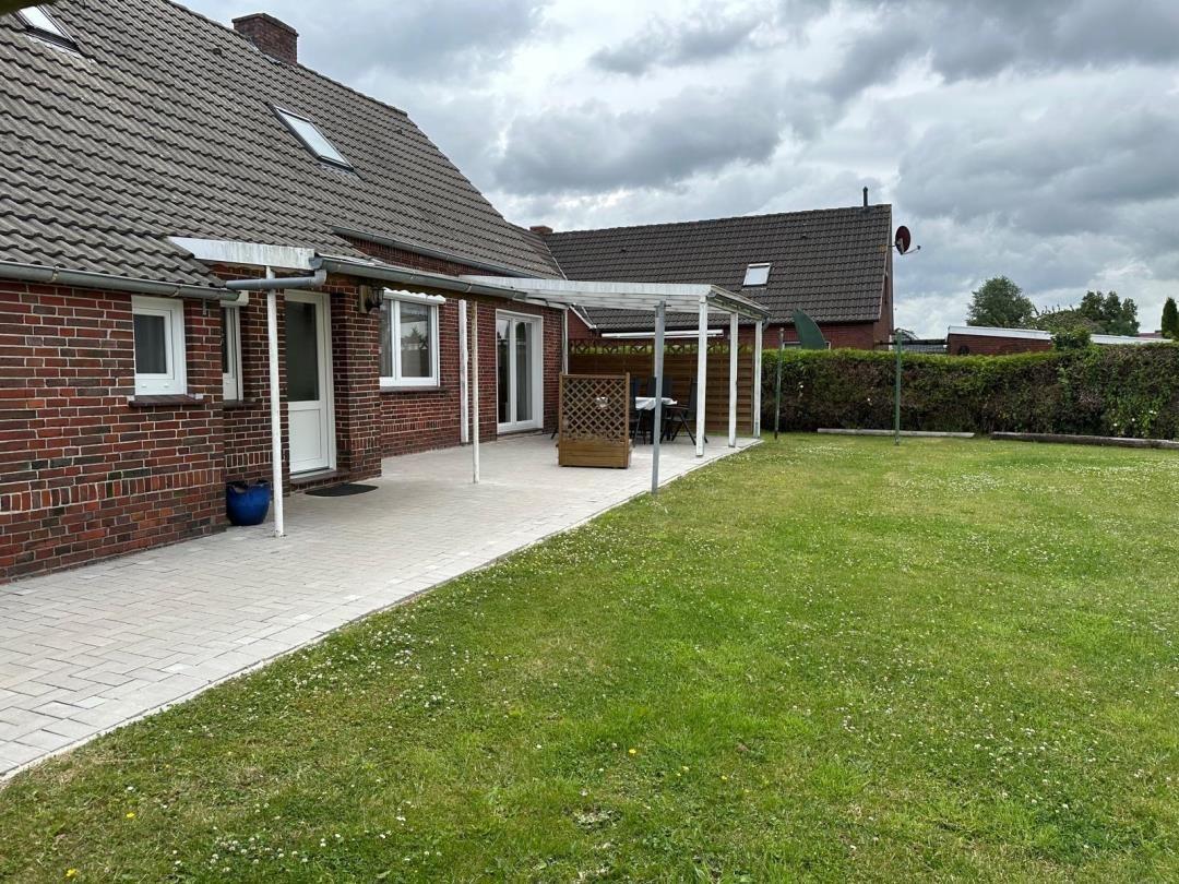 Haus mit Garten, Terrasse und Sitzgelegenheit im Freien.