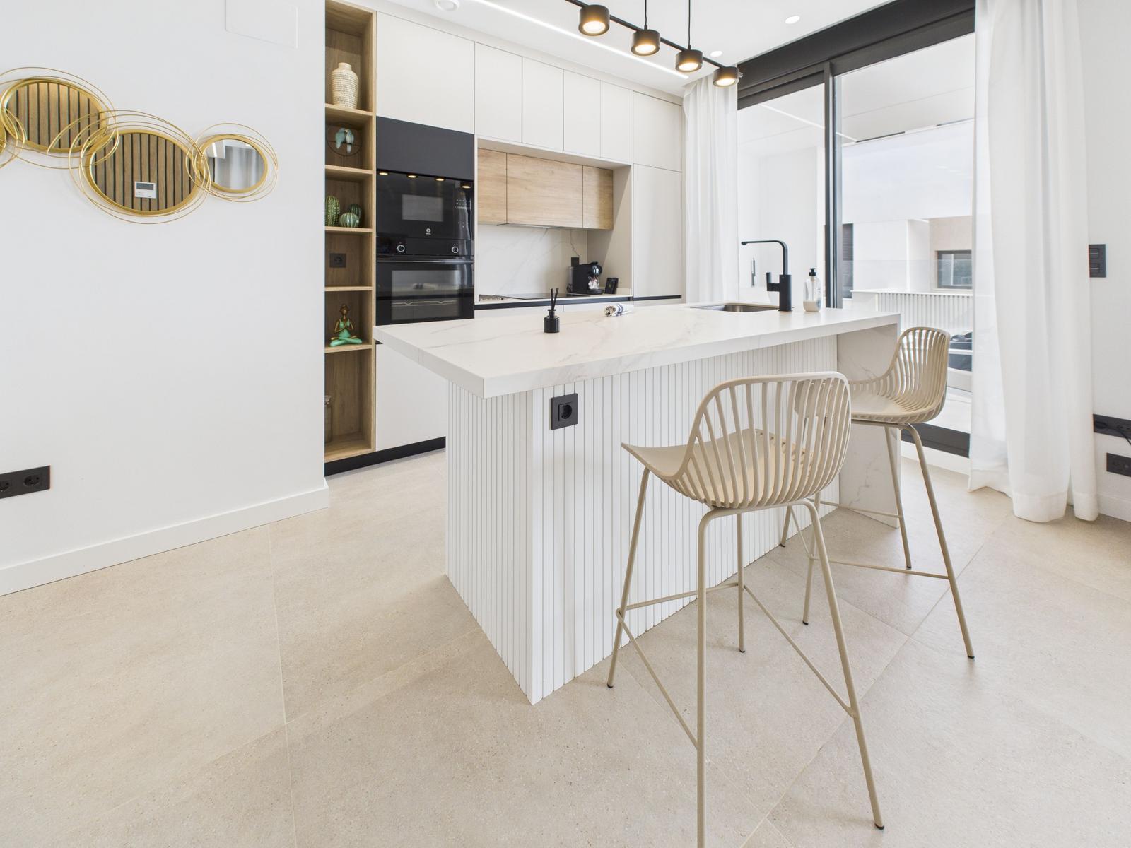 Modern kitchen with island, bar stools, and glass door to terrace.
