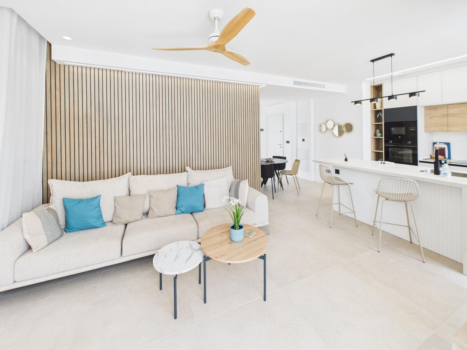 Living and dining area with sofa, kitchen island, and wooden wall