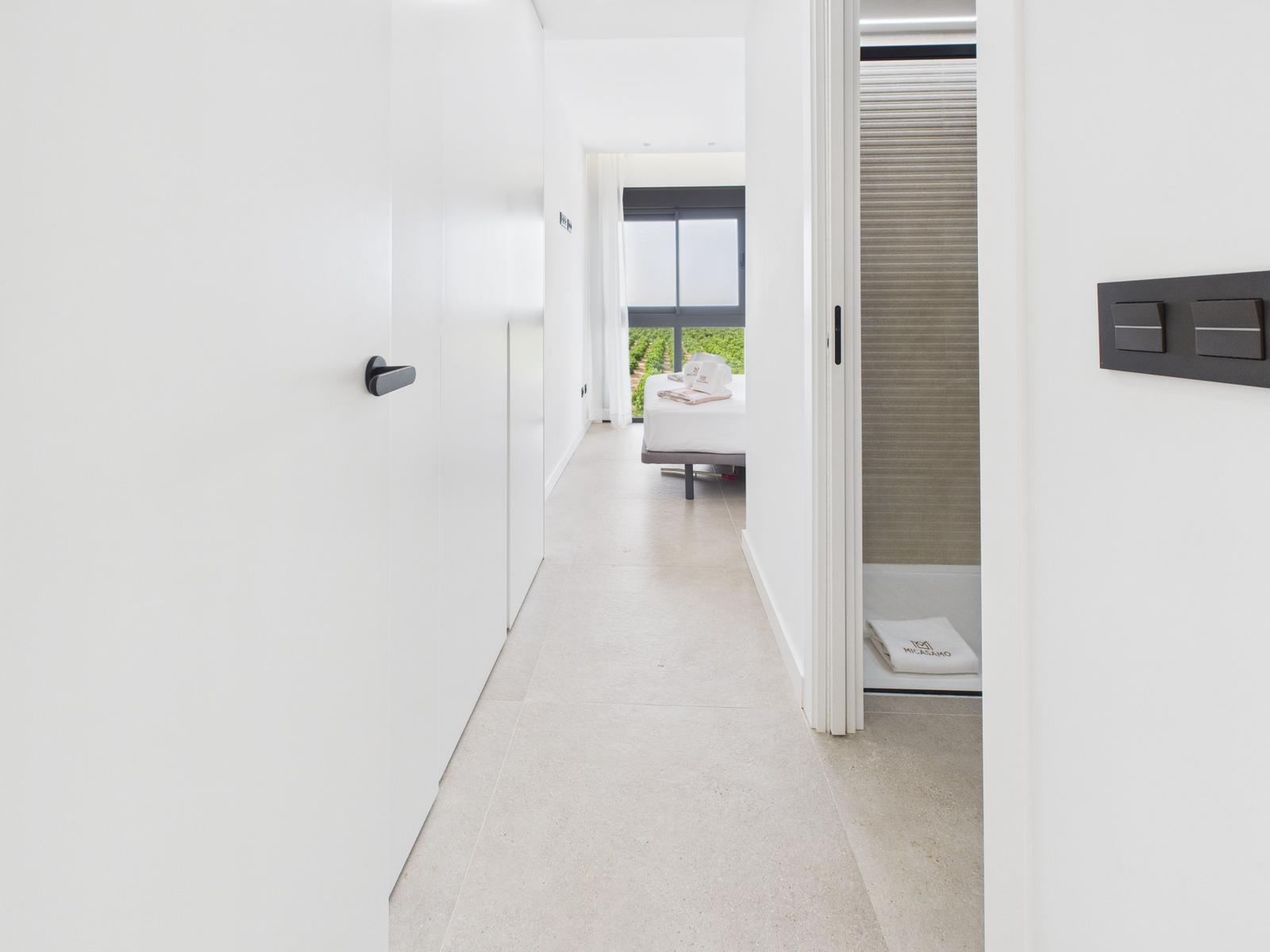 Hallway with view into bedroom and bathroom with roller blind.