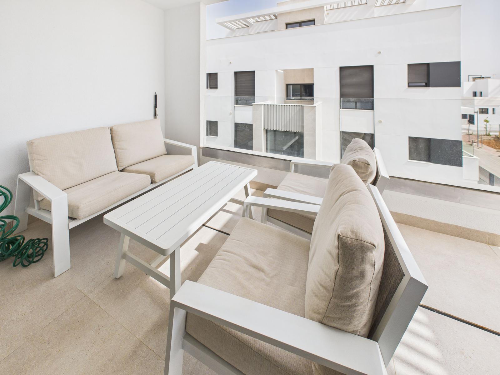 Terrace with white sofa, table, and seating. View of modern buildings.