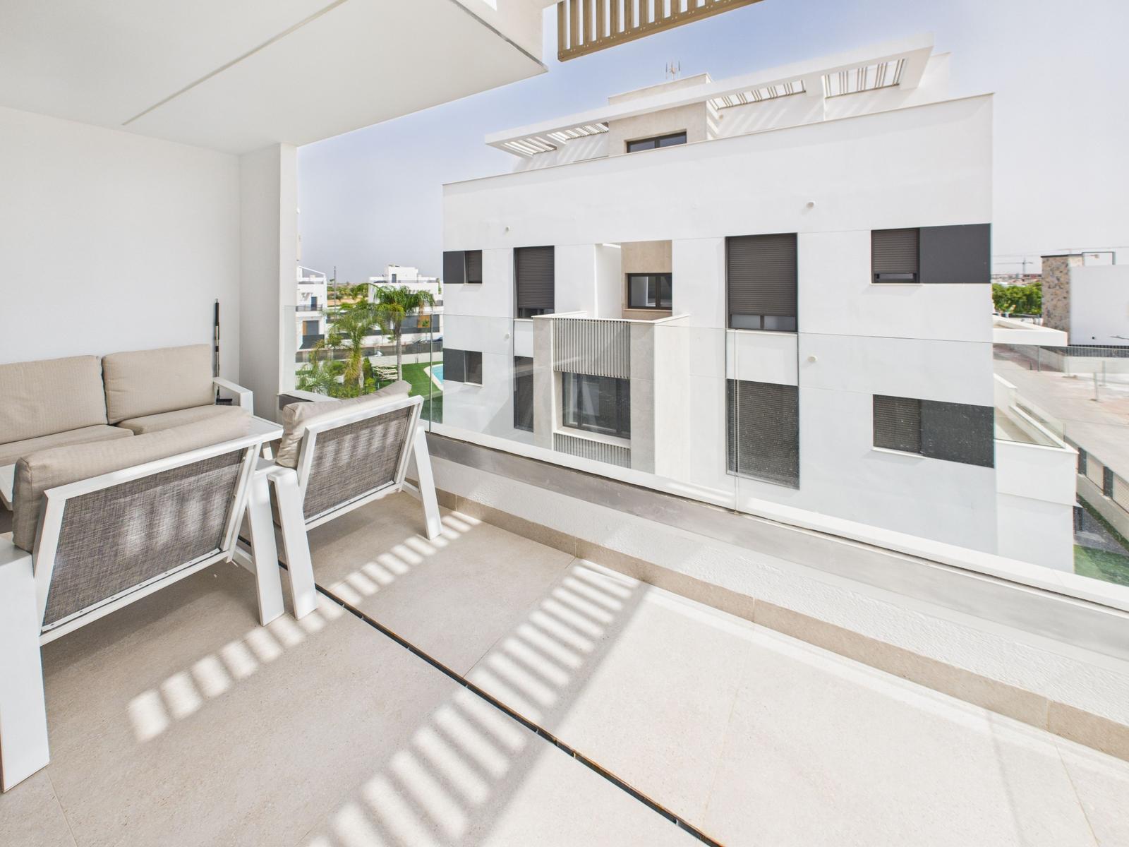 Terrace with seating area and view of modern buildings and pool area.