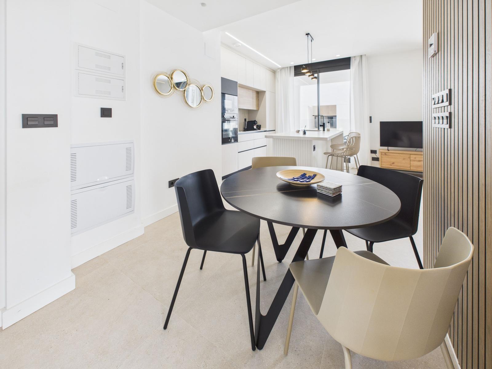 Dining area with round table and chairs. Kitchen and living area are visible.
