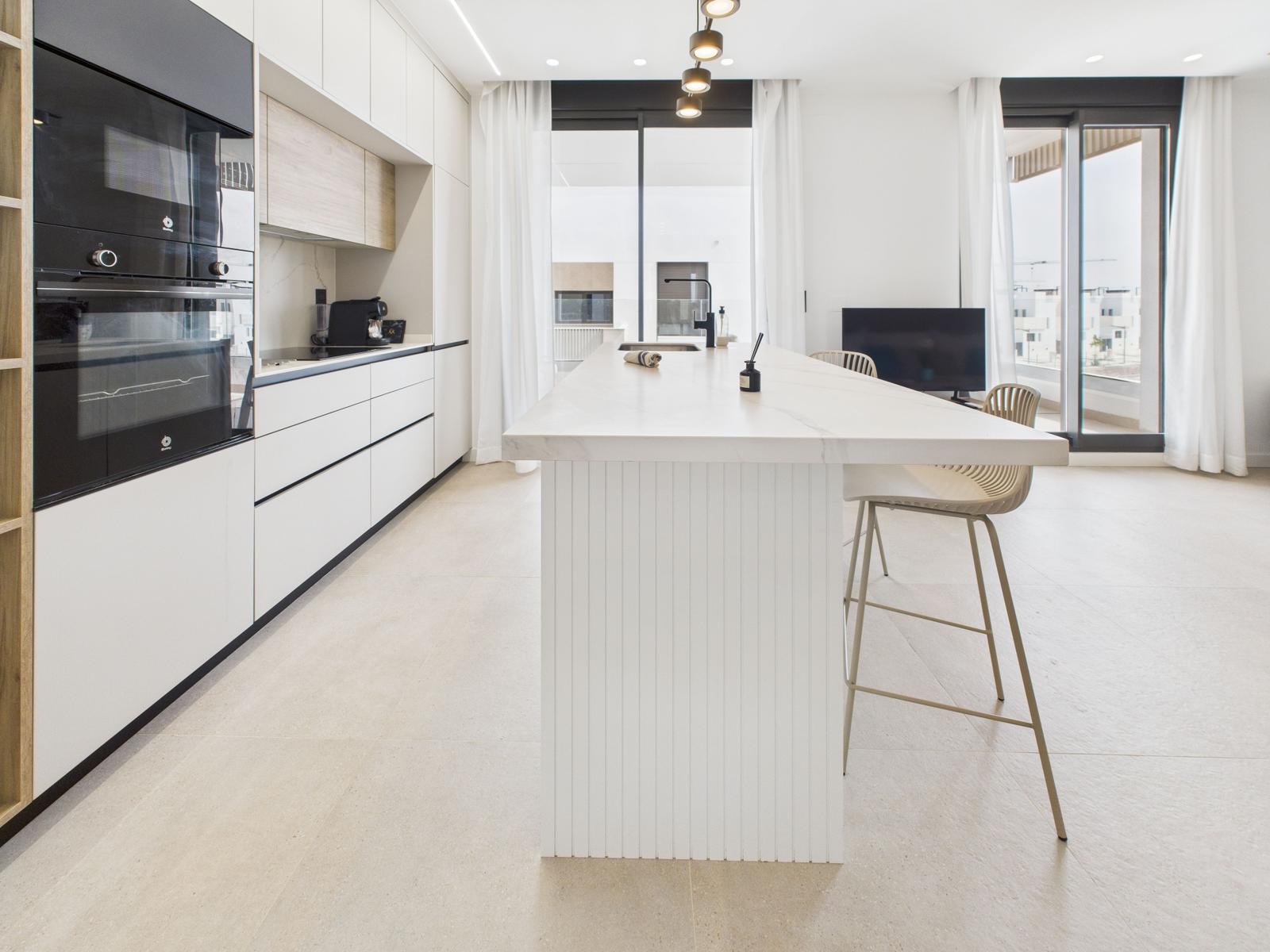 Modern kitchen with island, built-in oven, and large window view.