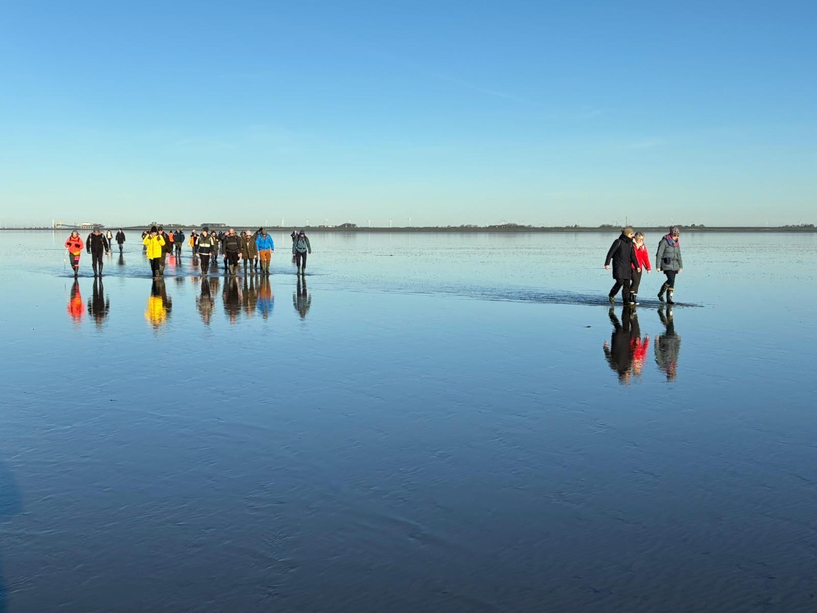 Gruppe wandert über gefrorenes Wasser unter klarem Himmel.