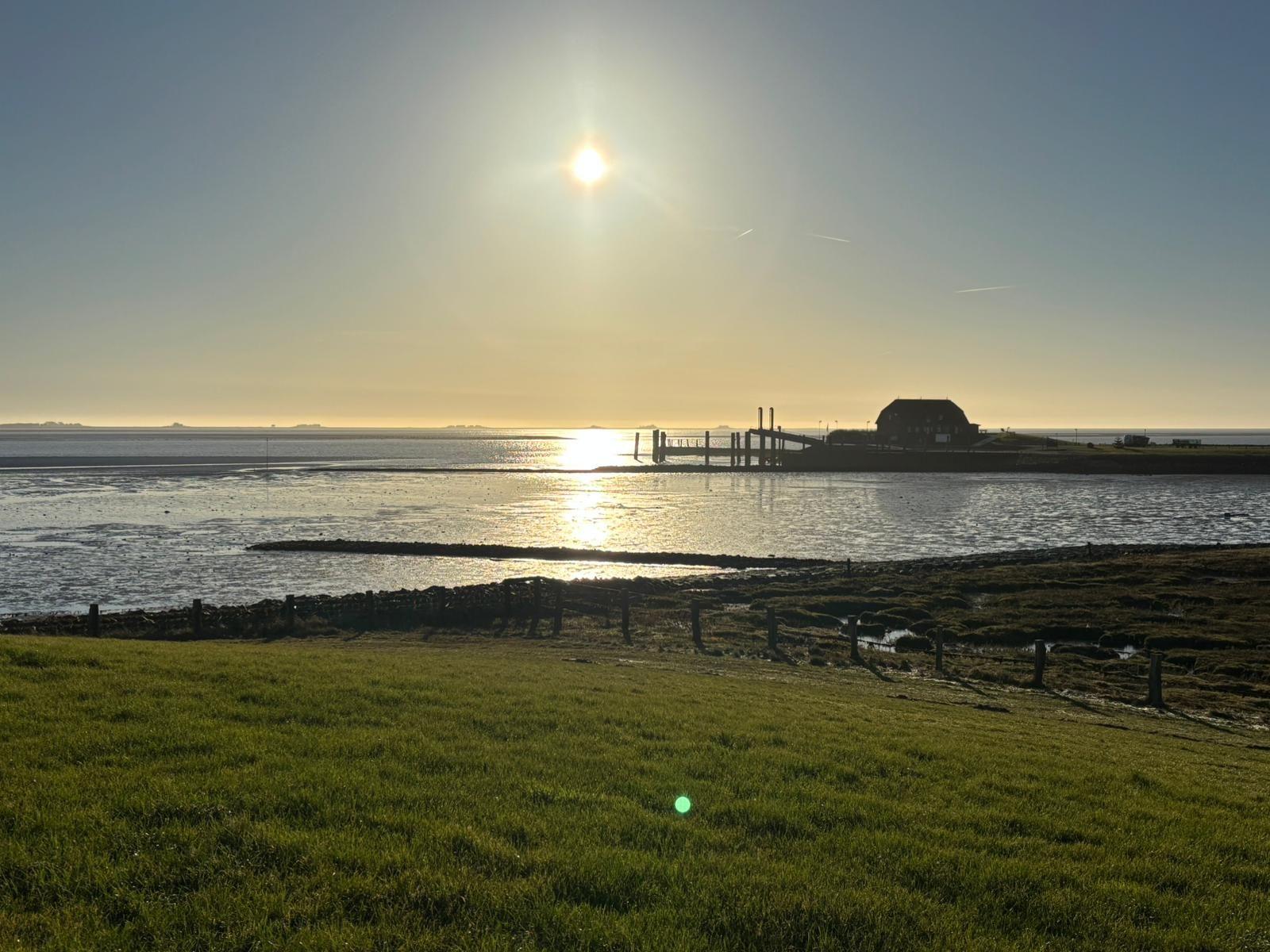 Sonnenuntergang über Wasser mit Blick auf Haus und Steg.
