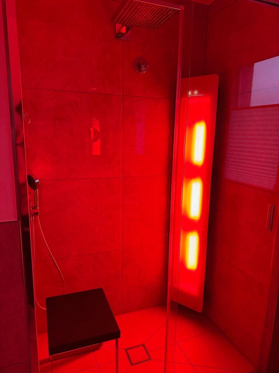 Dusche mit roter Beleuchtung und Sitzbank