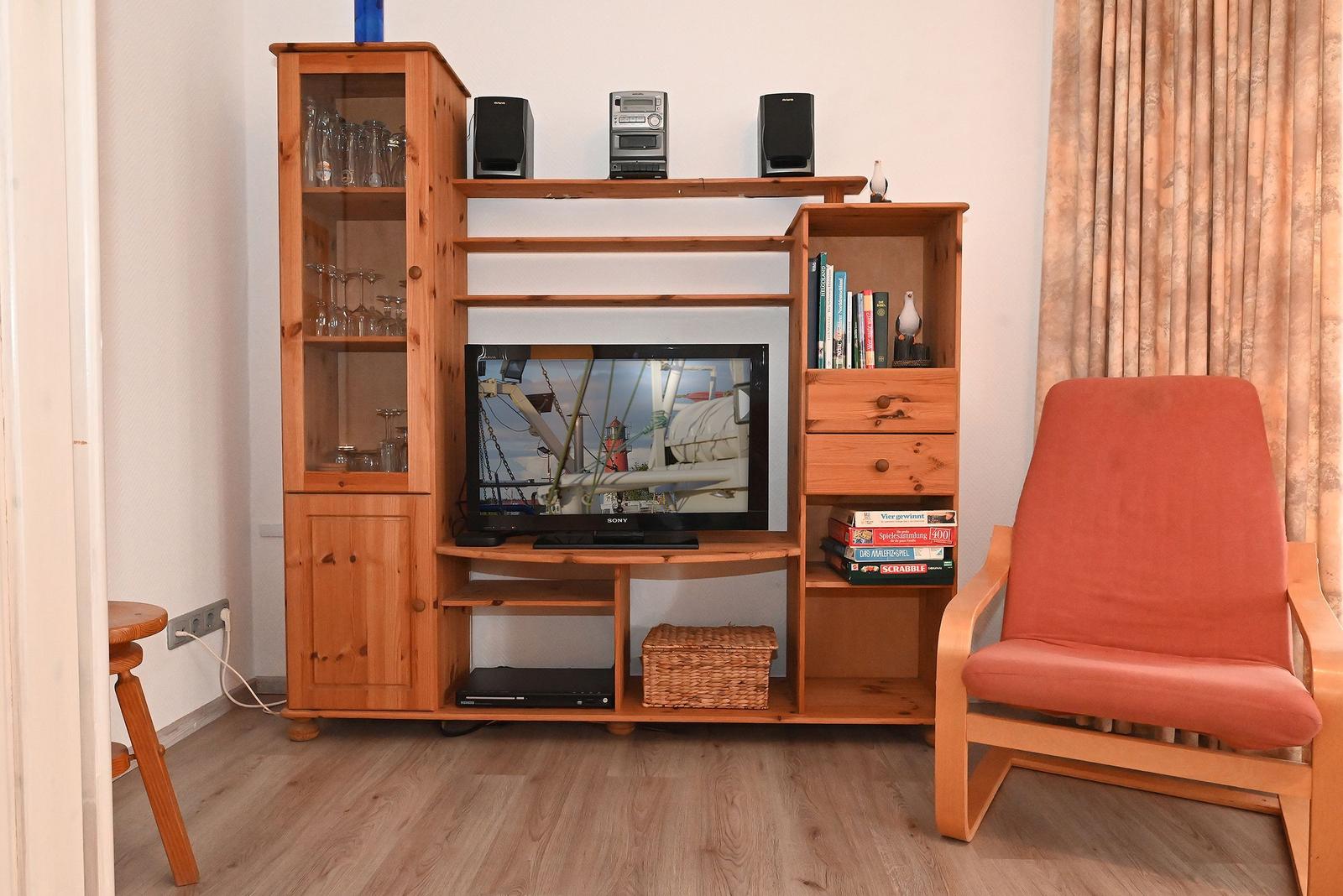 Ein Raum mit Holzmöbeln, Fernseher, Stuhl und Bücherregal.