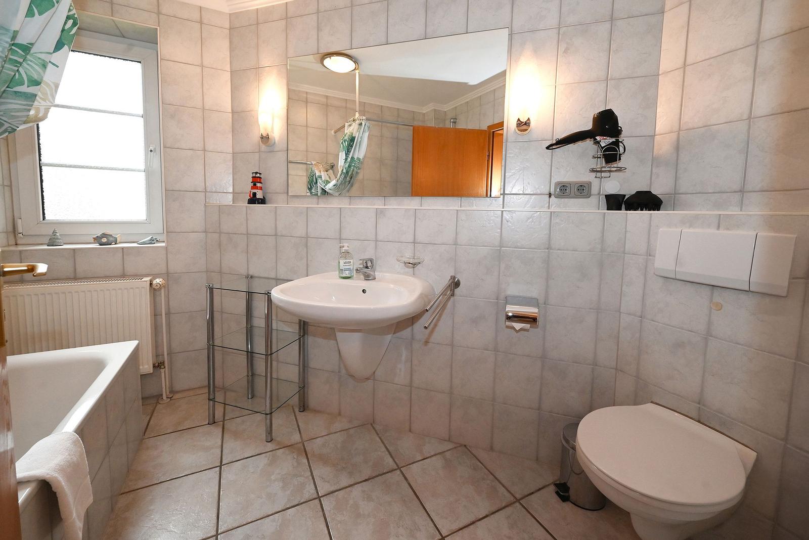 Badezimmer mit Badewanne, Waschbecken, Toilette und Spiegel.