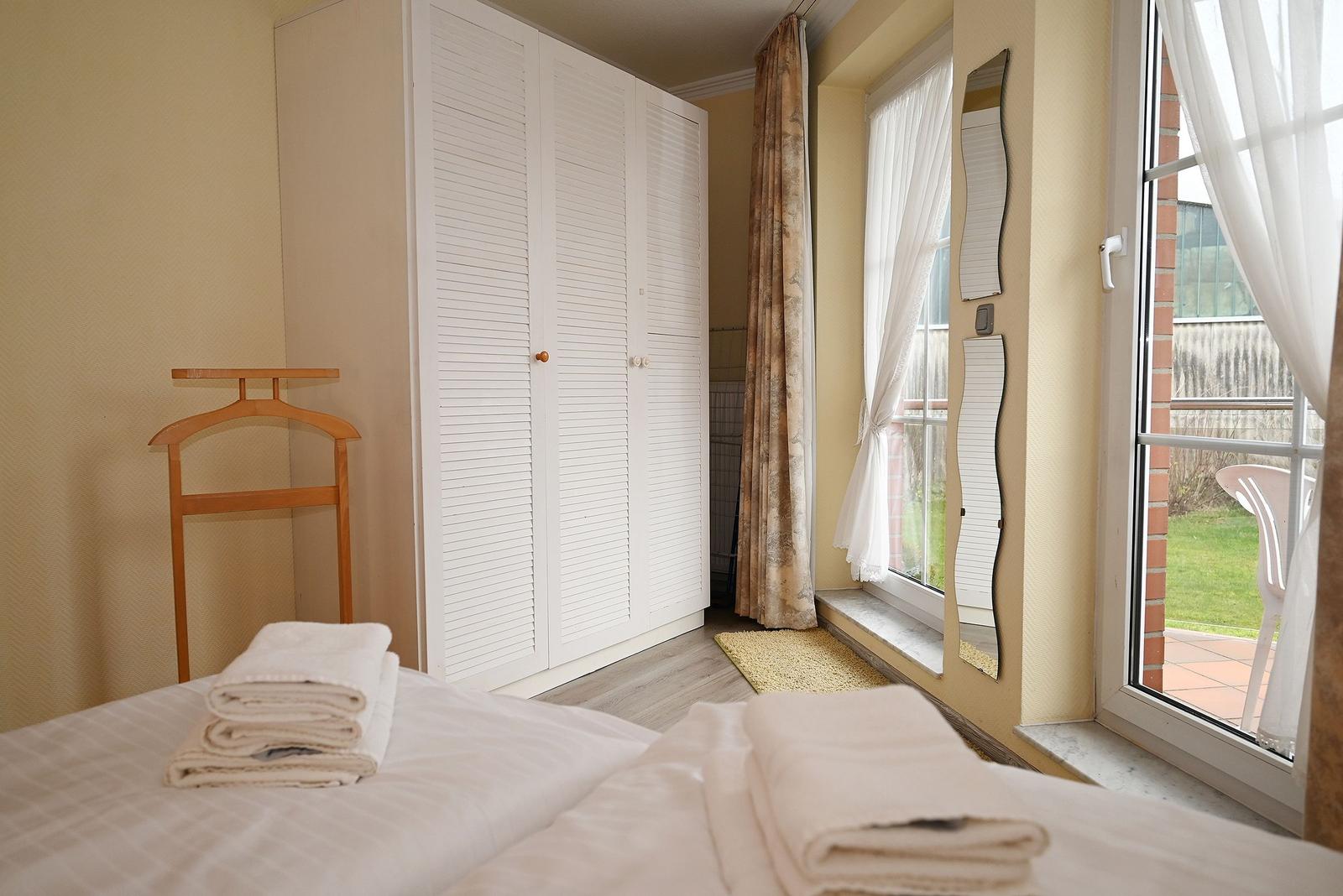 Schlafzimmer mit Doppelbett, Kleiderschrank und Fenster zur Terrasse.